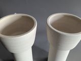two white vases sitting next to each other on a table