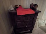 une petite armoire dans un coin de la salle de bains, sur laquelle est posée une serviette rouge