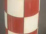 a red and white vase sitting on top of a red plate