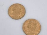 two gold coins sitting next to each other on a white surface