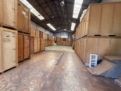 many wooden boxes in a large warehouse with a ladder