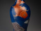un vase bleu orné d'un motif représentant un poisson rouge