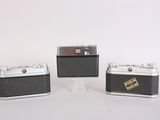 three small cameras sitting on top of each other on a white surface