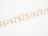 un gros plan sur un collier de perles blanches posé sur une surface blanche