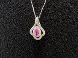 a close up of a woman ' s necklace with a pink stone