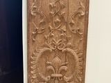 carved wood panel on the wall of a bathroom with a toilet in the corner
