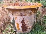 a rusted pot sitting in the middle of the grass