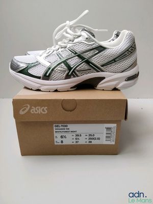 a white and green running shoe sitting on top of a box