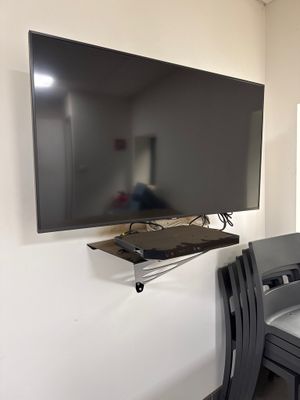 a flat screen tv mounted on the wall above a dining room table