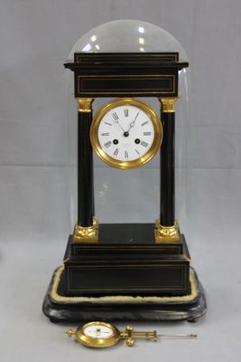 une horloge noire et dorée surmontée d'un dôme en verre