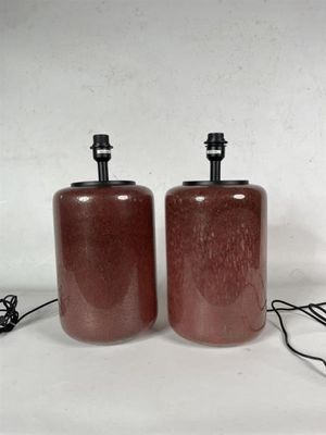 une paire de lampes en verre rouge avec des abat-jours noirs sur fond blanc