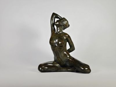 une statue en bronze représentant une femme assise à genoux