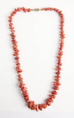un collier de perles de corail rouge sur fond blanc