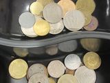 un bol noir contenant des pièces de monnaie, avec une cuillère à l'intérieur