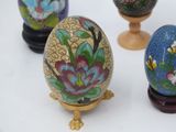three decorative eggs are sitting on a stand on a white surface
