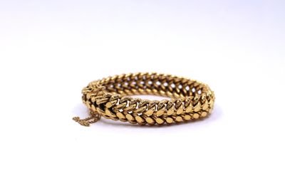 a close up of a gold chain bracelet on a white background