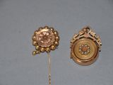 a gold brooch and a gold pin on a blue surface