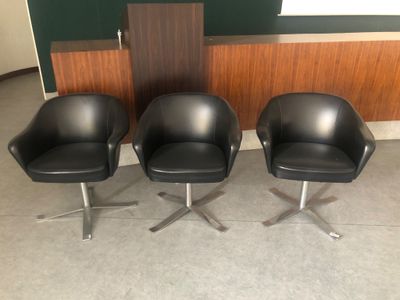 trois fauteuils en cuir noir placés les uns à côté des autres dans une pièce