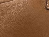 the back of a brown purse with a chain hanging from it ' s handle