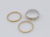 three gold and silver rings on a white surface