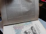 a person holding an open book on top of a table