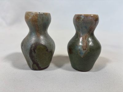 two green vases sitting on top of a white surface