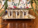 quatre verres à shot posés sur un plateau en argent, sur une table