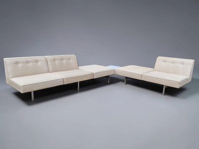 two white couches sitting next to each other on a gray surface