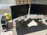 un bureau sur lequel se trouvent deux écrans d'ordinateur et un téléphone