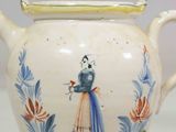 a white tea pot with a blue and yellow design on it