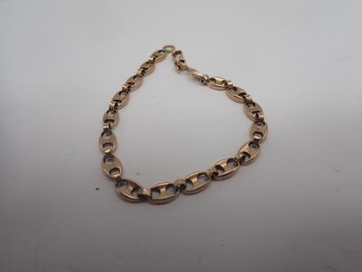 gros plan d'un bracelet en chaîne en or sur une surface blanche