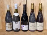 several bottles of wine are lined up on a shelf in front of a wooden wall