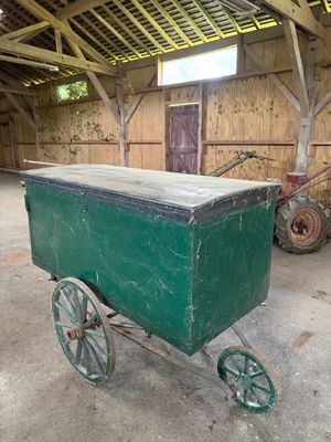 un chariot vert posé à l'intérieur d'une grange au toit en bois