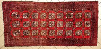 an old red rug with a pattern on it is hanging on a chain link fence