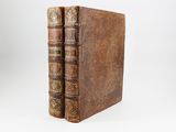 two old books sitting on top of each other on a white surface