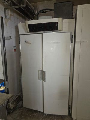 an image of a refrigerator in a kitchen with a microwave on top of it