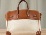 a brown and white handbag sitting on top of a wooden table
