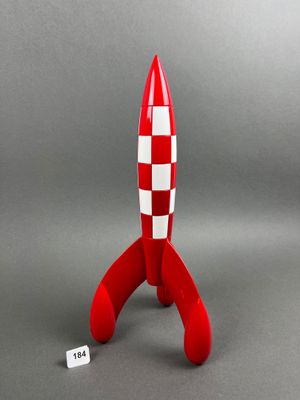 a red and white toy rocket sitting on top of a gray surface