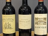 trois bouteilles de vin rouge sont alignées sur une table