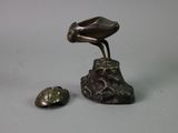 a bronze statue of a bird on a rock next to a shell