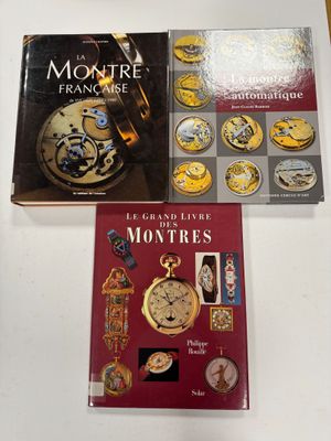 three books on a table with a clock and a book cover