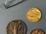 three gold coins and a silver coin sitting on a table