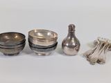 three silver dishes and spoons sitting on a white surface