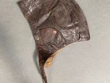 brown leather hat with ear flaps on top of a gray surface