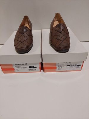 une paire de chaussures en cuir marron exposée dans une boîte blanche