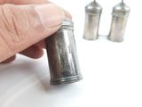 a person holding a silver pepper shaker in their hand
