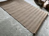 un tapis marron posé par terre, à côté d'une pile de cartons