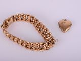 a close up of a gold chain bracelet with a heart charm