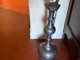 a silver vase sitting on the floor next to a door