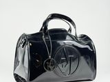 the black handbag is sitting on a white surface with a chain around it
